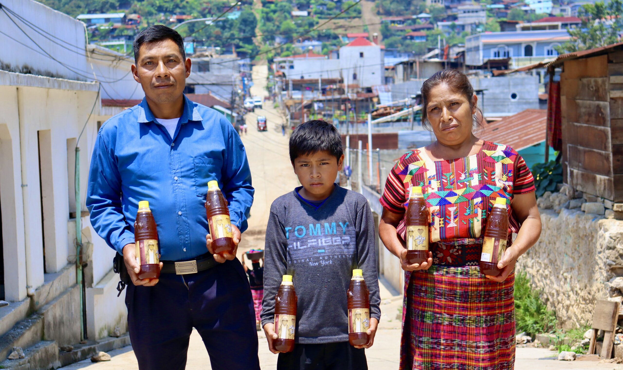 The Otsuma family, members of the Maya Ixil coffee co-op, proudly displaying the honey they produced, which provides crucial supplemental income during the "thin months" of food insecurity.